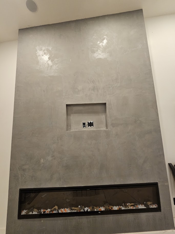 Decorative gray Venetian plaster accent wall with a recessed niche above a modern linear fireplace.