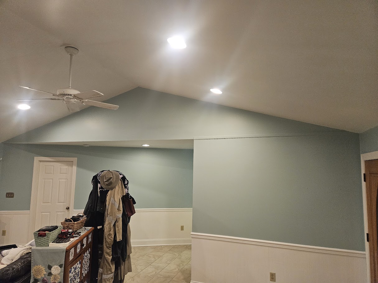 Interior painting project featuring soft sage green walls, white wainscoting, and recessed ceiling lighting.